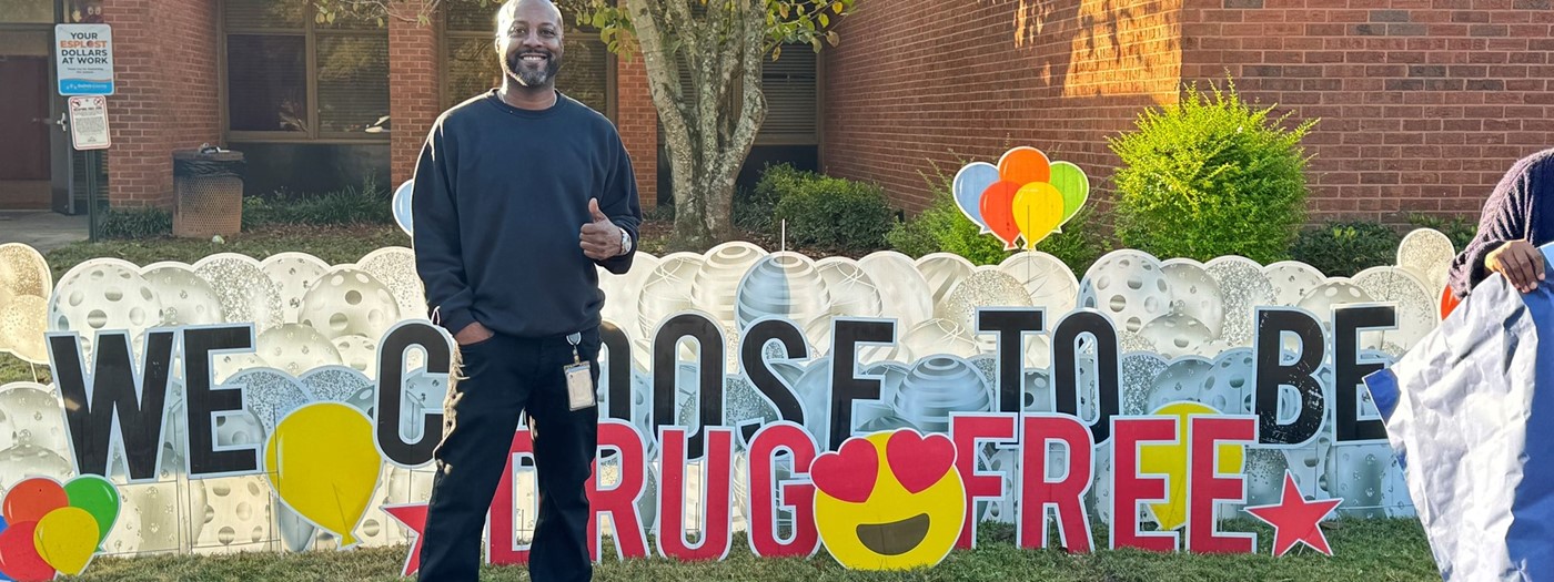 Lopez standing in front of sign that says We choose to be drug free
