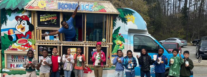 Kona Ice Truck with seller and children eating Kona Ice 