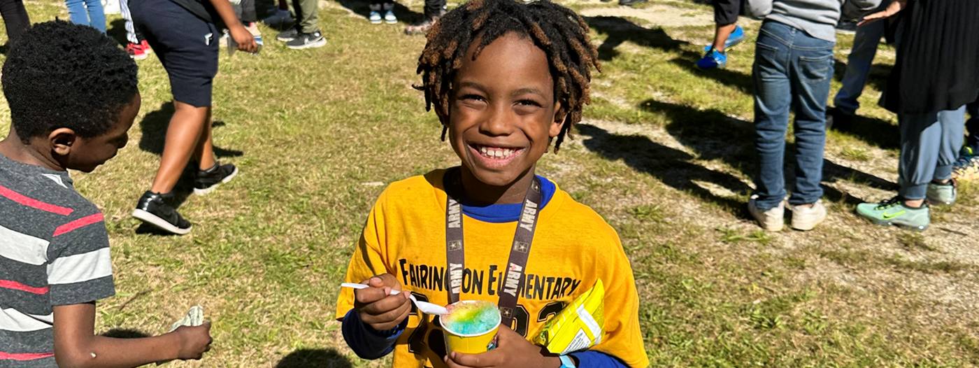 young boy with locs  with yellow shirt on smiling. 