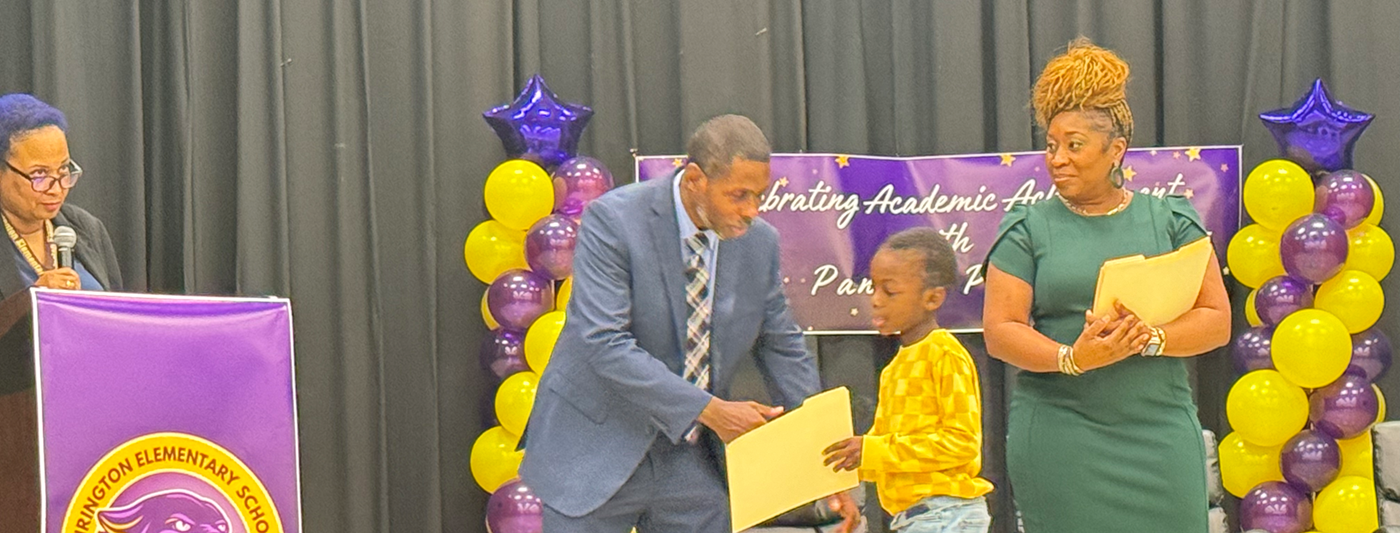 Honors day Mr. Clowers giving a student his certificate with Mrs. Northern standing on stage 